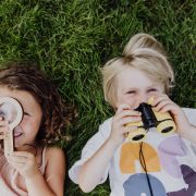 Spelende kinderen in het gras met Spriet vergrootglas en verrekijker